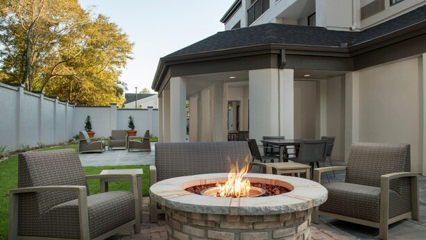 A patio area with a stone fire pit, outdoor seating, and a covered section with a table and chairs. - Courtyard by Marriott Dothan (Dothan)