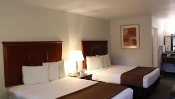 A hotel room with two beds, a nightstand with a lamp, a painting on the wall, and a bathroom visible through an open door.
