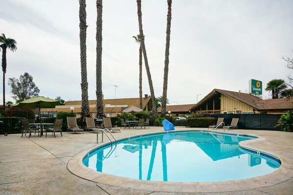 A pool area with lounge chairs, a covered table, and a sign for Vagabond Inn.