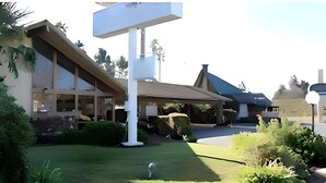 A building with a large sign, a covered outdoor area, and a well-maintained lawn. - Rodeway Inn Santa Clara El Camino Real (Santa Clara)