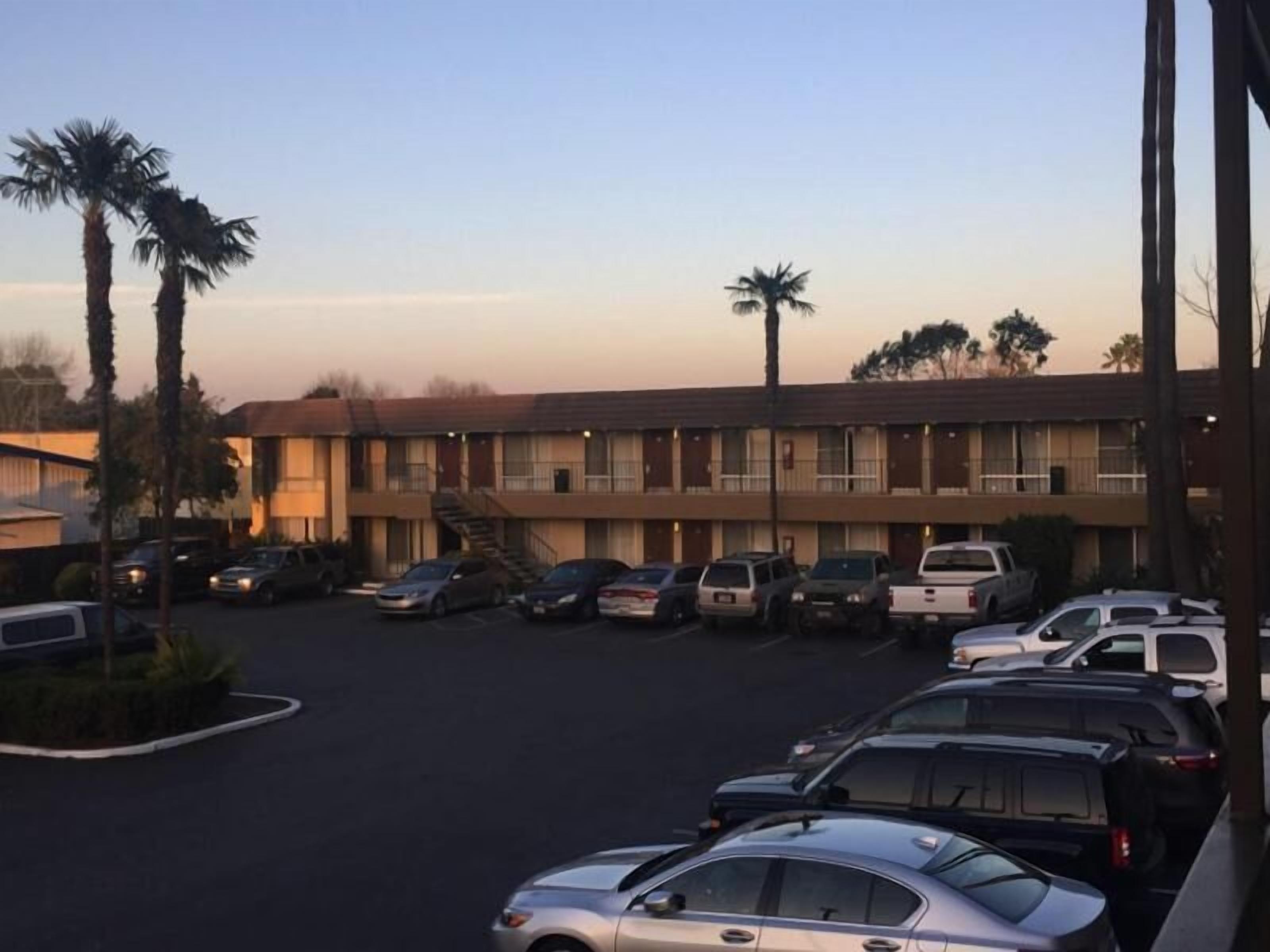 A motel with a parking lot and several cars parked.