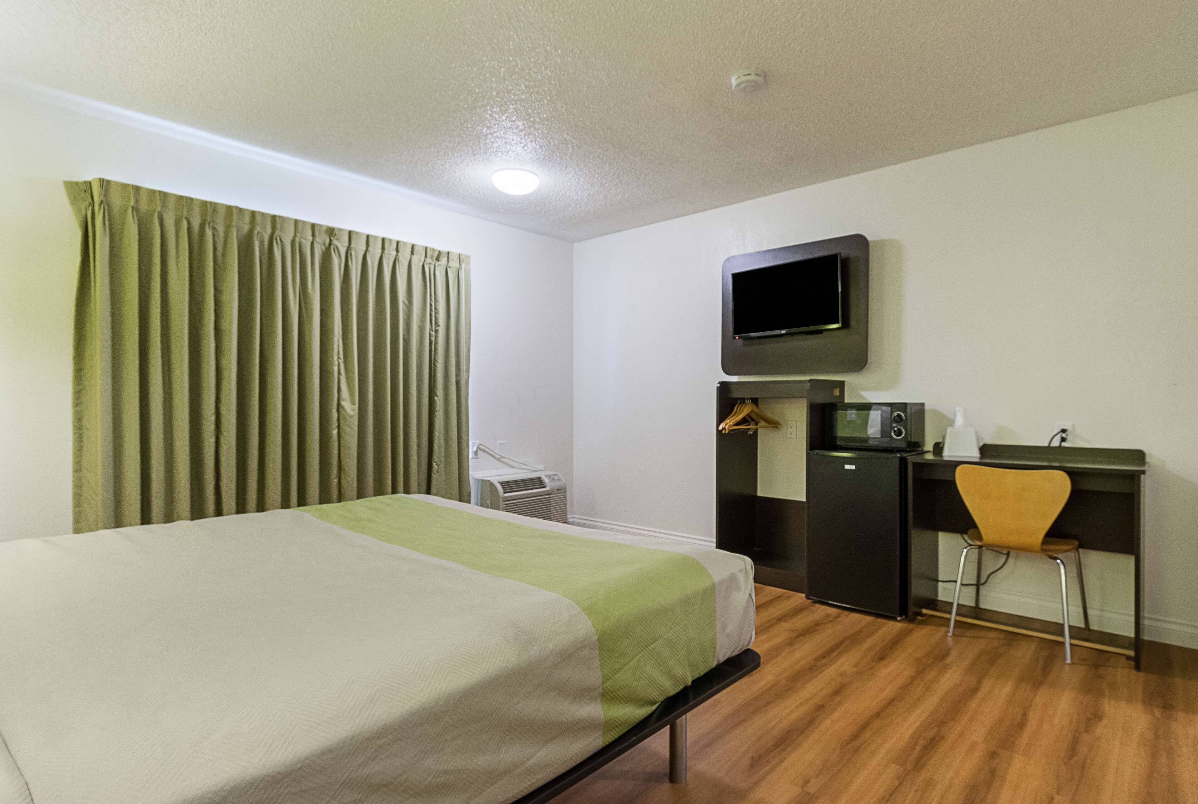 Une chambre d’hôtel équipée d’un lit, d’un bureau avec une chaise, d’une télévision et d’un four à micro-ondes.