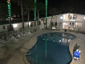Una piscina con sillas de descanso y un pequeño edificio al fondo.