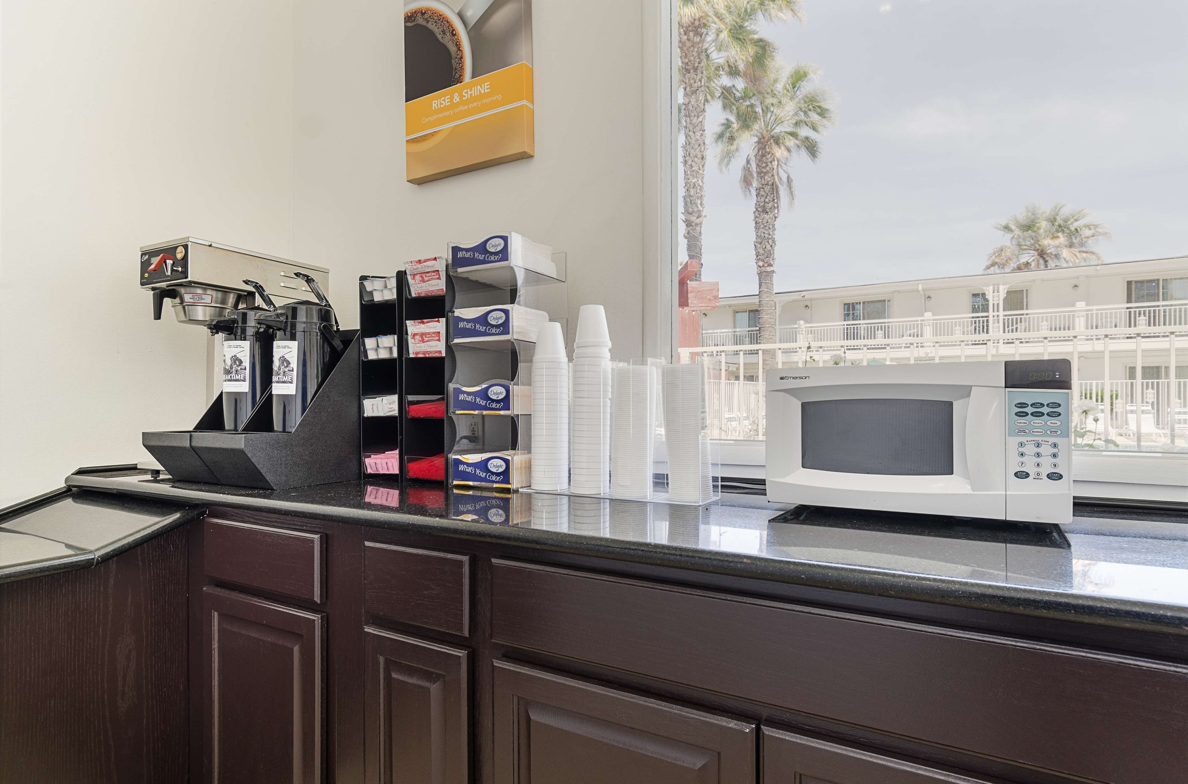 A coffee station with a coffee machine, cups, and a microwave.