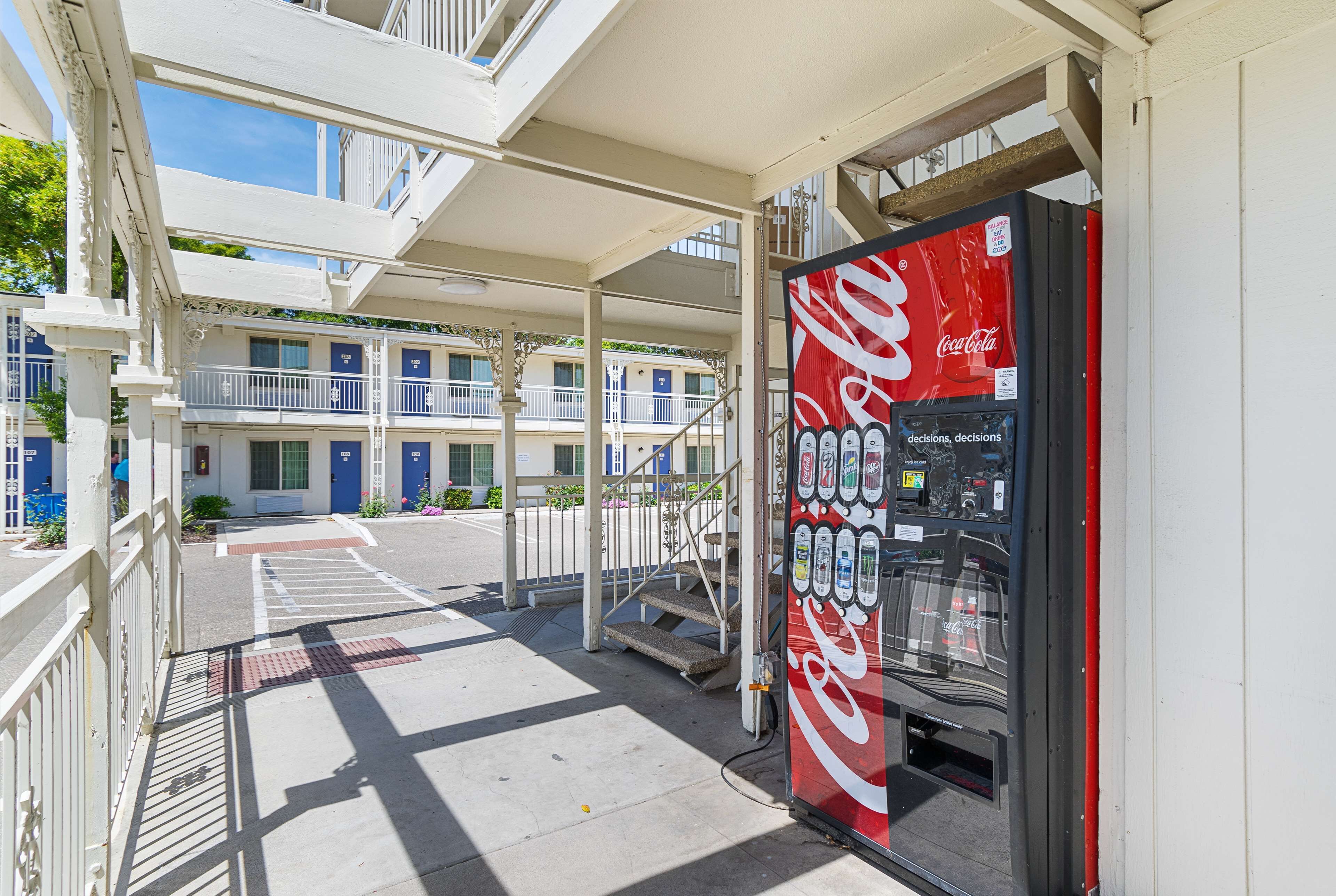 A Coca-Cola vending machine on a sidewalk with a building in the background.