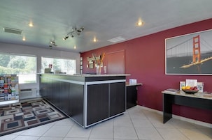 Una cocina moderna con una isla central, una pared de acento roja y un cuadro con la imagen del Puente Golden Gate.
