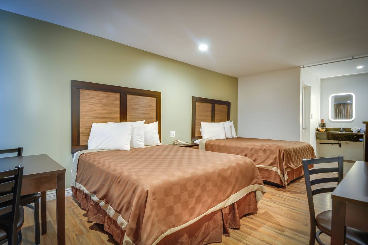 A hotel room with two beds, a desk, and a chair.