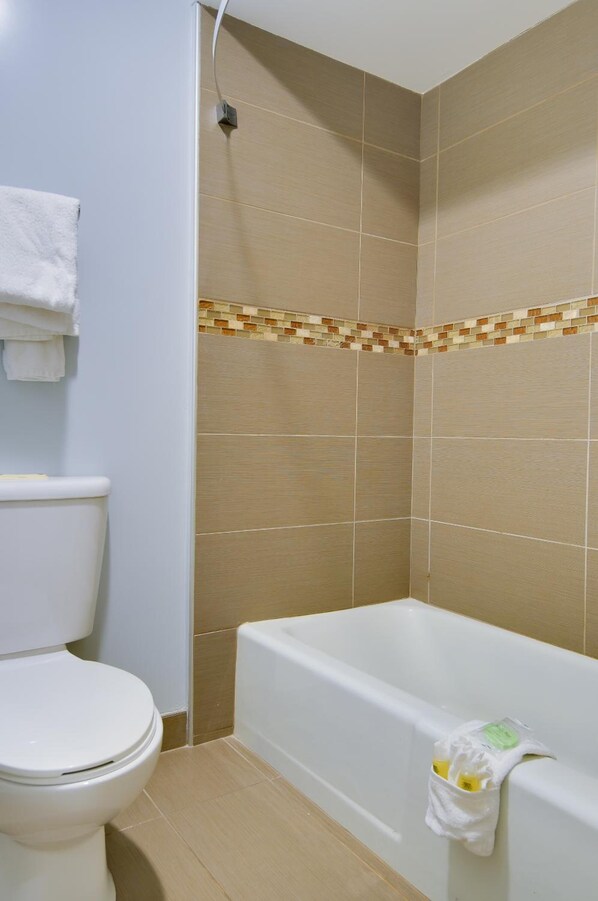 A bathroom with a toilet, a bathtub, and tiled walls.