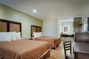 A hotel room with two beds, a desk, and a mirror.