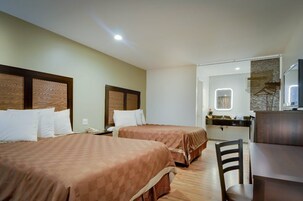 Habitación de hotel con dos camas, un escritorio y un espejo.