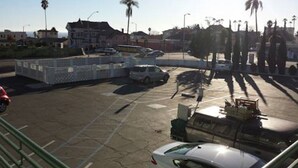 A parking lot with several cars, a motorcycle, and a building in the background.