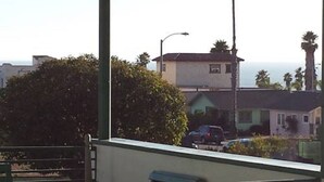 A balcony with a view of a residential area, including houses and palm trees.