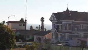 A two-story house with a prominent bay window, a gabled roof, and a visible chimney.