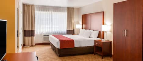 A hotel room with a bed, bedside tables, a TV, a wardrobe, and a window with curtains.