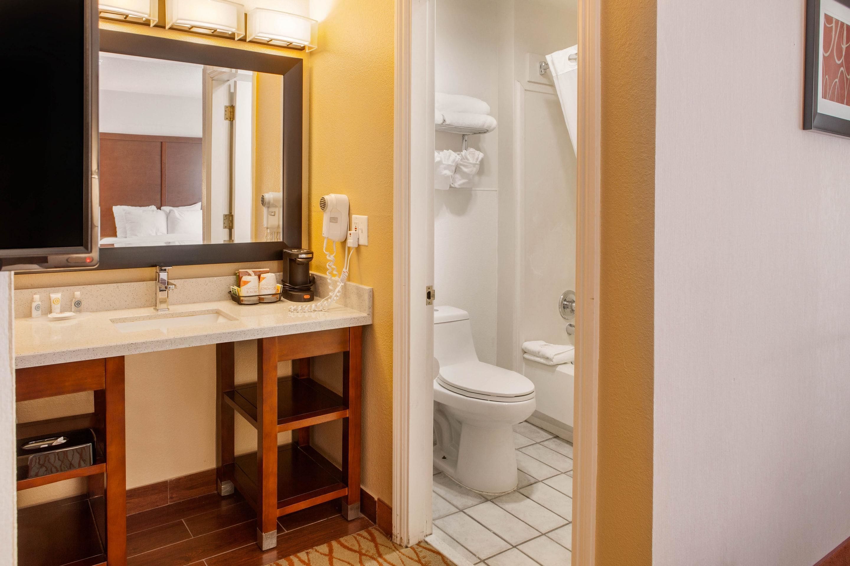 Une salle de bain d’hôtel avec un lavabo, un miroir et des toilettes.