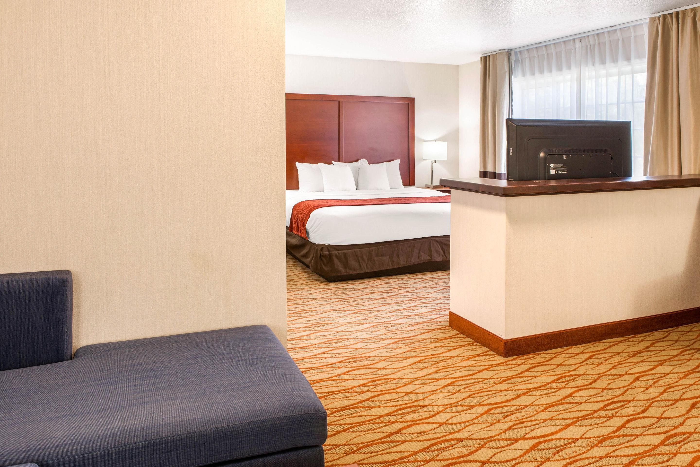 Ein Hotelzimmer mit Bett, Fernseher, Schreibtisch und Stuhl.