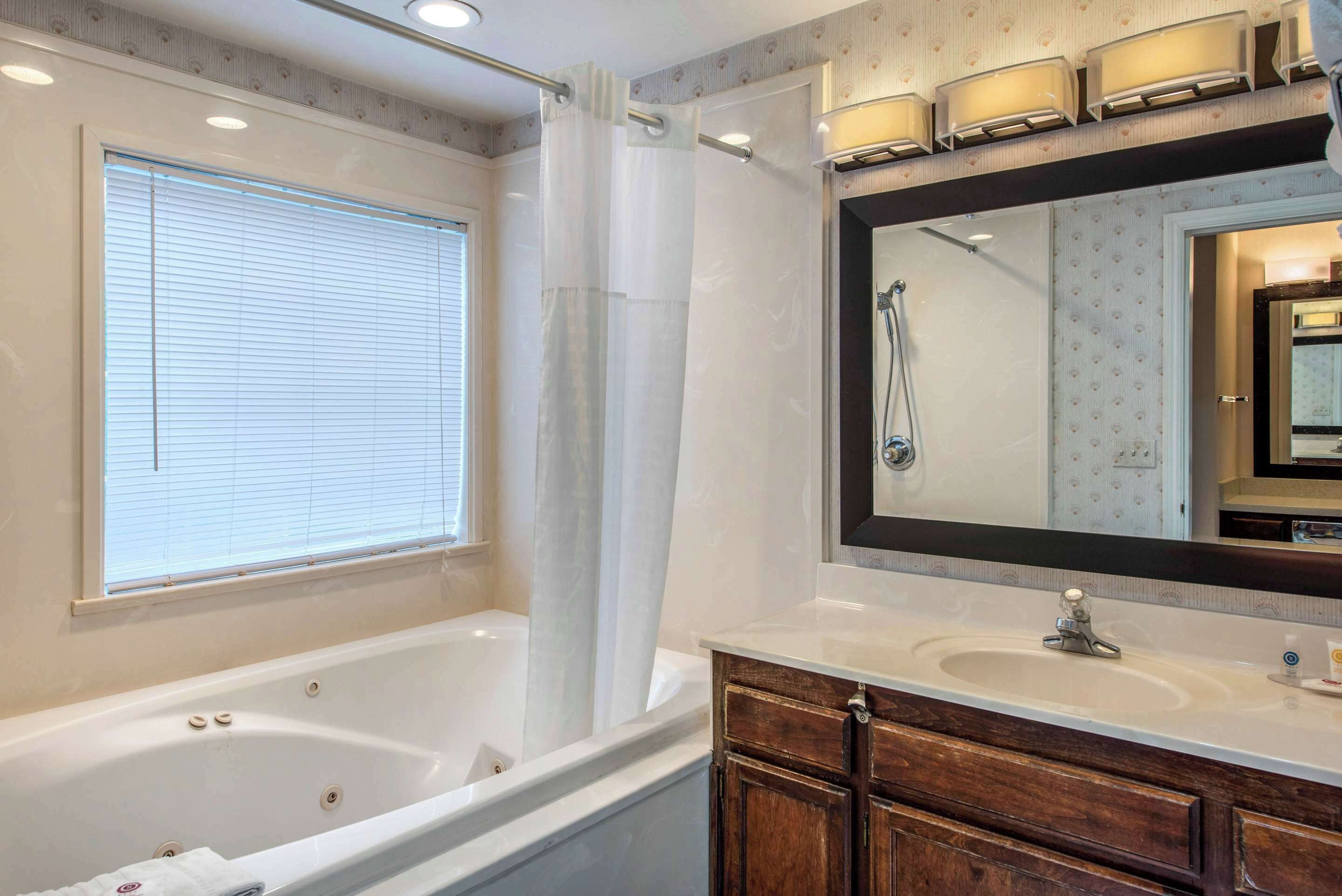 A bathroom with a bathtub, vanity, and a large mirror.