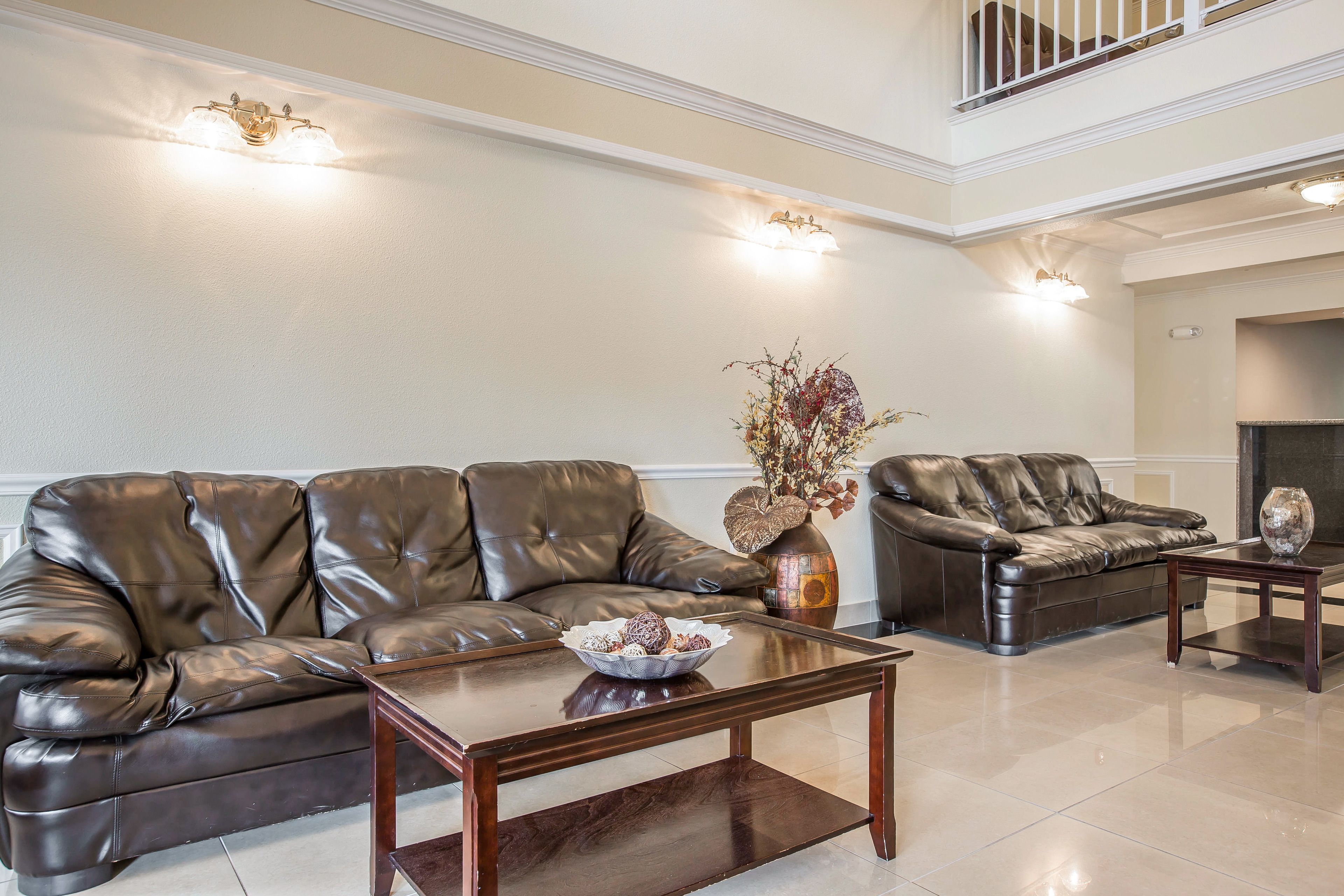 A spacious living room with two leather sofas, a coffee table, and decorative vases.