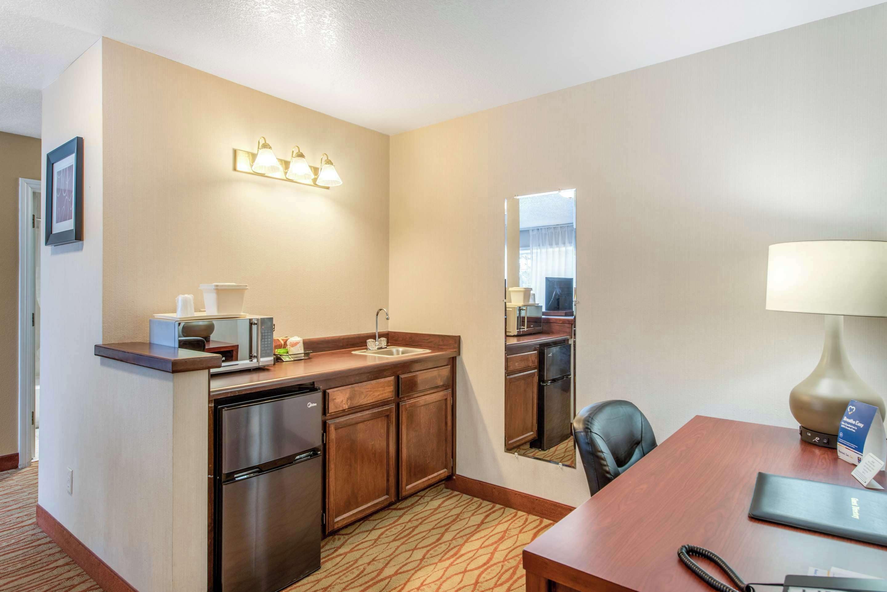 Une chambre d’hôtel compacte comprenant un coin cuisine, un espace repas et un miroir.