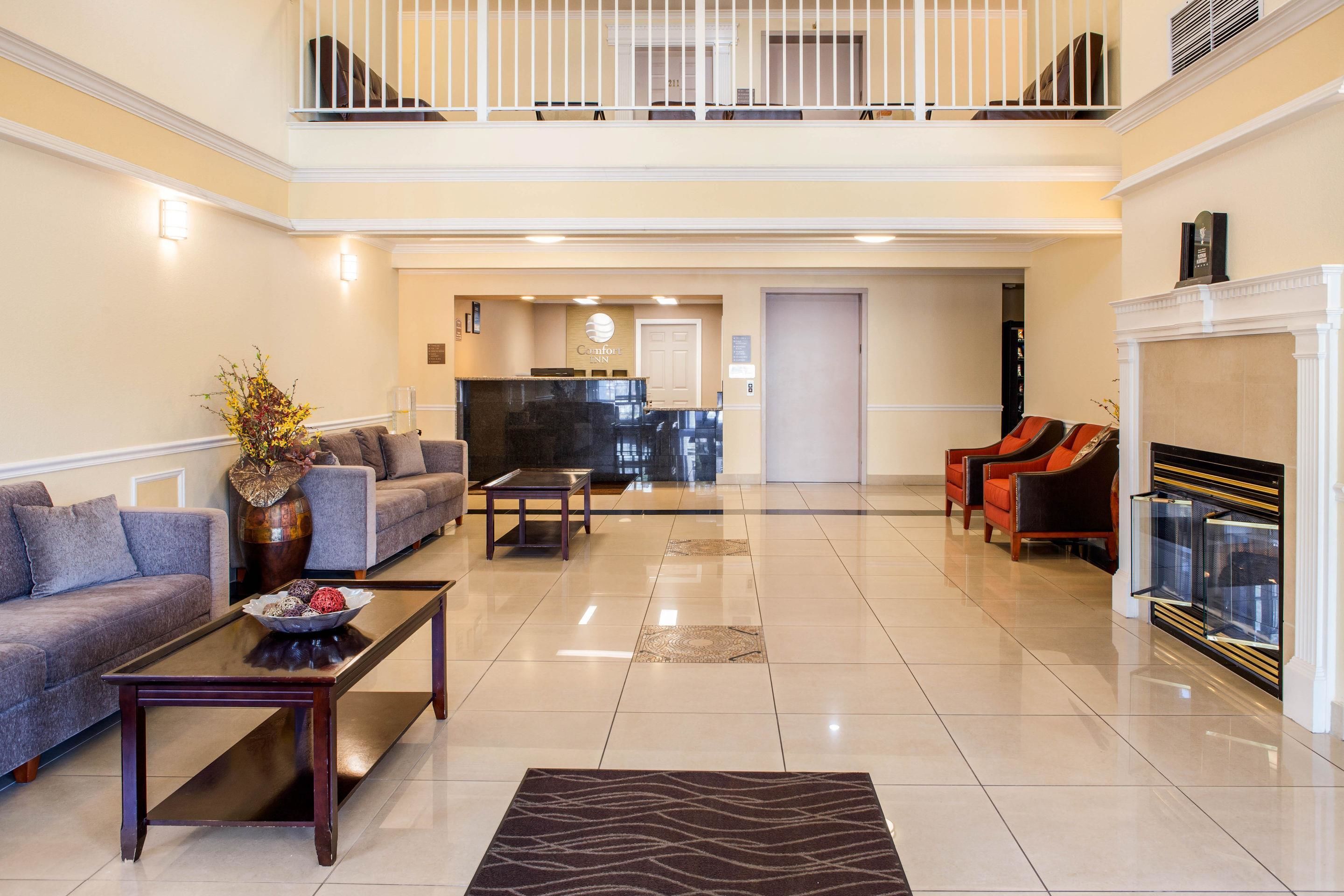 A spacious living area with a piano, sofas, and a fireplace.