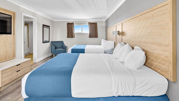 A modern hotel room with a large bed, a desk, and a TV.