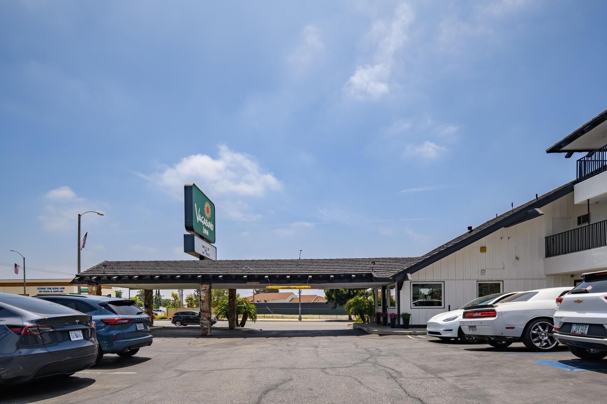 A parking lot with several cars, a gas station, and a building with a sign that reads "VAGABOND INN".