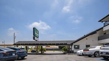 A parking lot with several cars, a gas station, and a building with a sign that reads "VAGABOND INN".