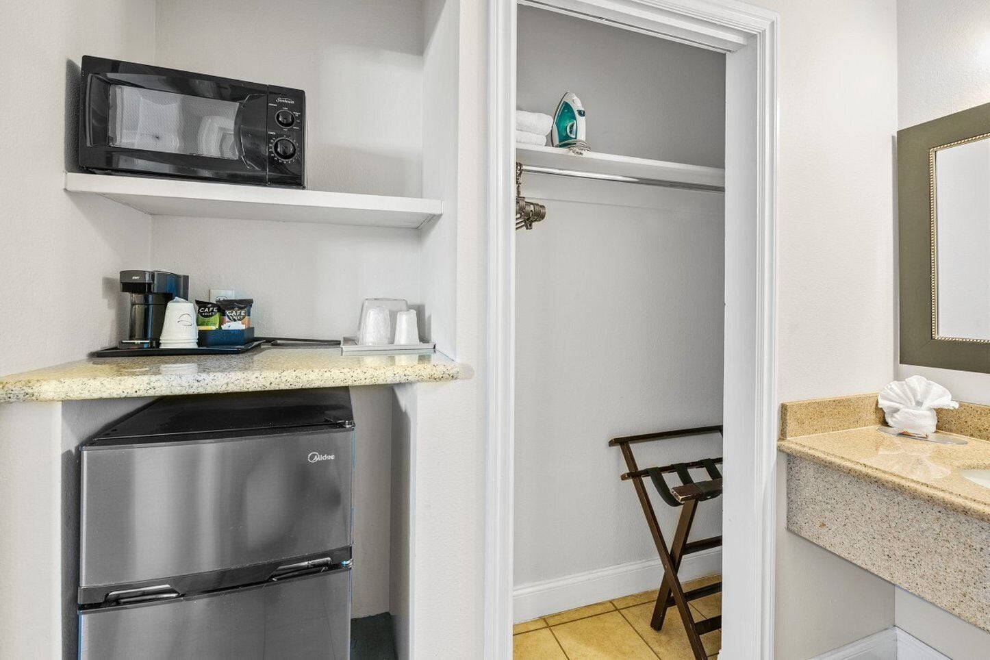 Una kitchenette compacta con microondas, cafetera y refrigerador.