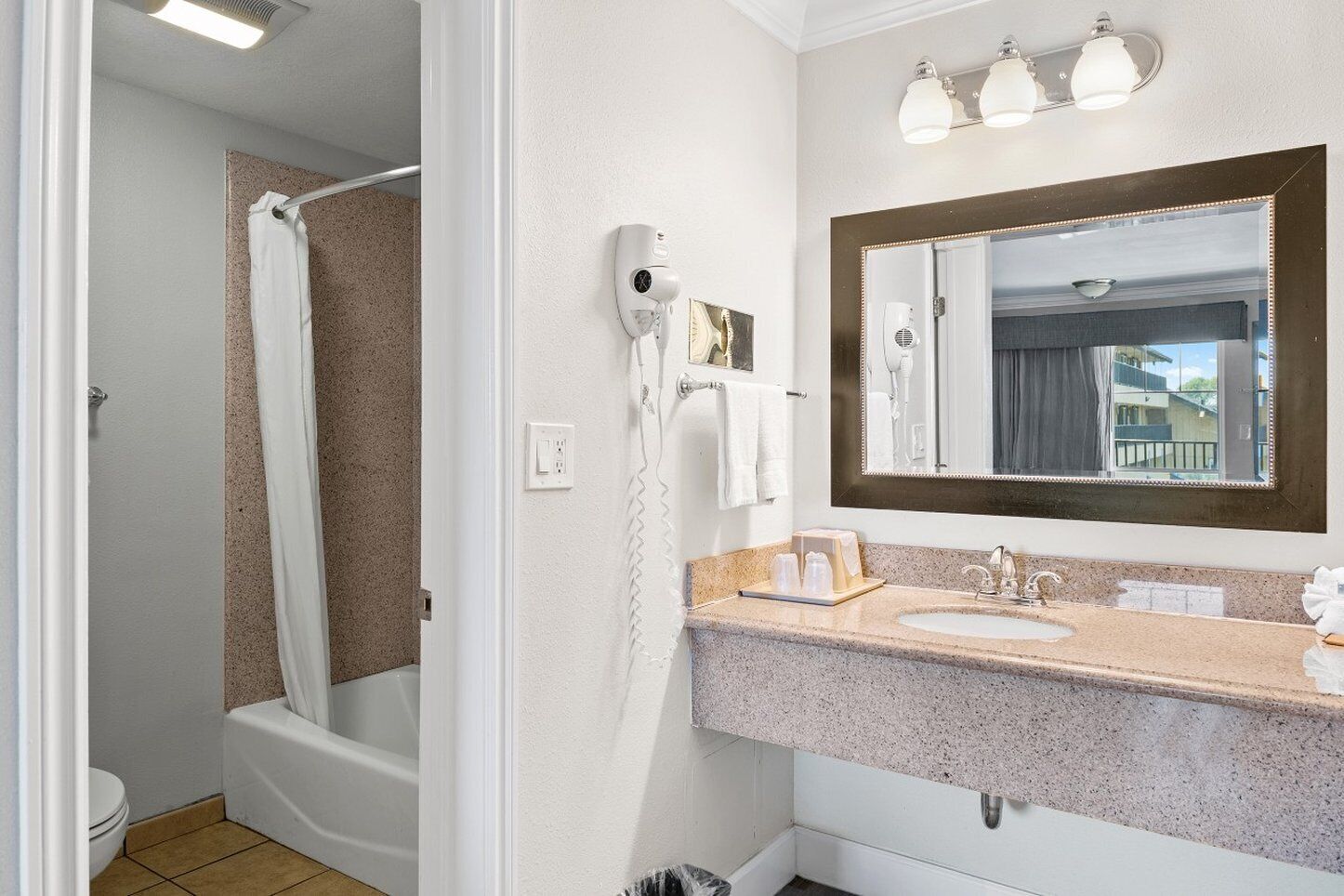 A bathroom with a shower, a sink, a mirror, and a hairdryer.