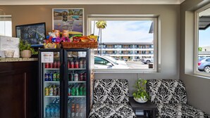 A lobby with a seating area, a beverage cooler stocked with drinks, and a window view of a parking lot.