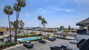 A parking lot with several cars, a swimming pool, and palm trees.