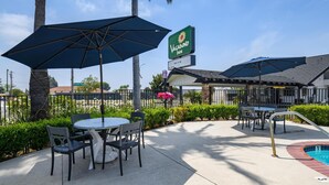 An outdoor seating area with tables and chairs, a pool, and a sign for Vagabond Inn.