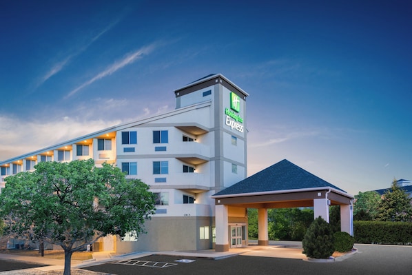 A Holiday Inn Express hotel with a modern design, featuring a prominent tower with the hotel’s logo, a covered entrance, and a parking lot. - Holiday Inn Express Colorado Springs Airport by IHG (Colorado Springs)