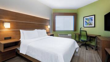 A hotel room with a large bed, bedside tables, a desk, an office chair, a window, and a framed picture on the wall.