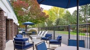 An outdoor patio area with seating and a table, surrounded by a stone wall and a metal fence. - Hampton Inn Loveland (Loveland)