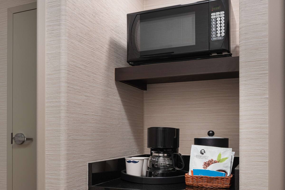 A kitchenette with a microwave, coffee maker, and a basket of coffee pods.