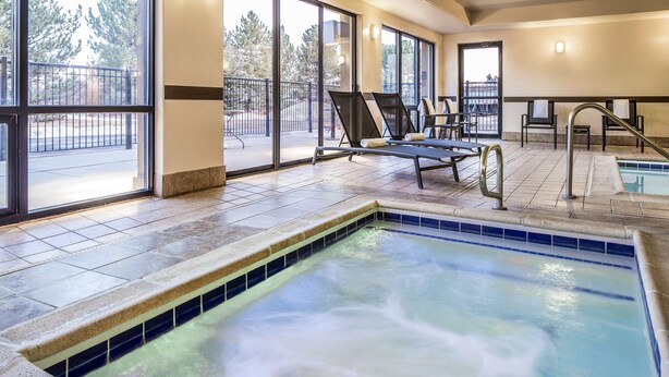 A heated indoor pool area with lounge chairs and a view of the outside. - Hampton Inn Loveland (Loveland)