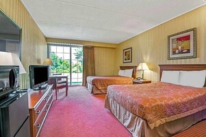 Habitación de hotel con dos camas, televisión, escritorio y ventana con cortinas.
