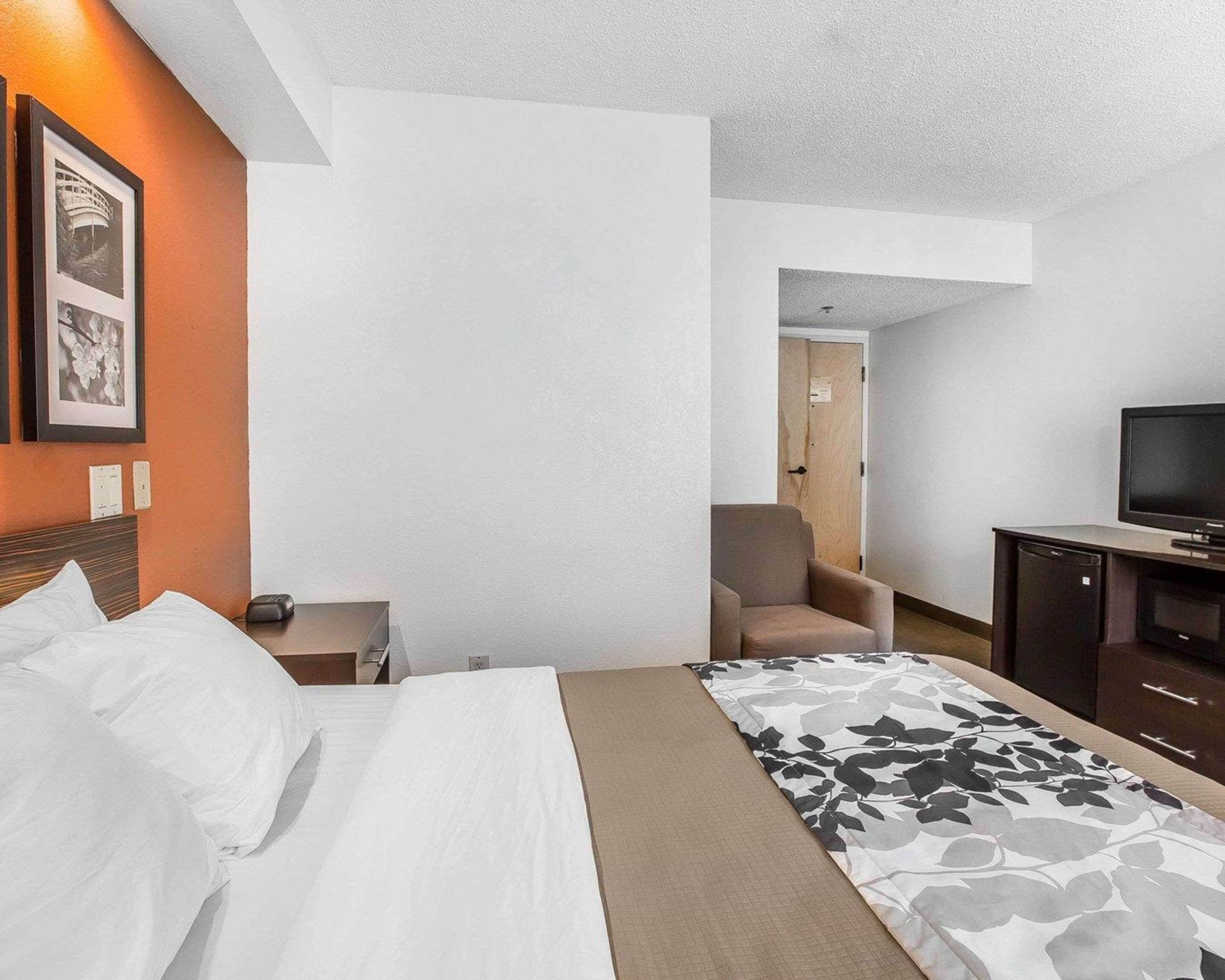A hotel room with a bed, a chair, a television, and a desk with a computer.