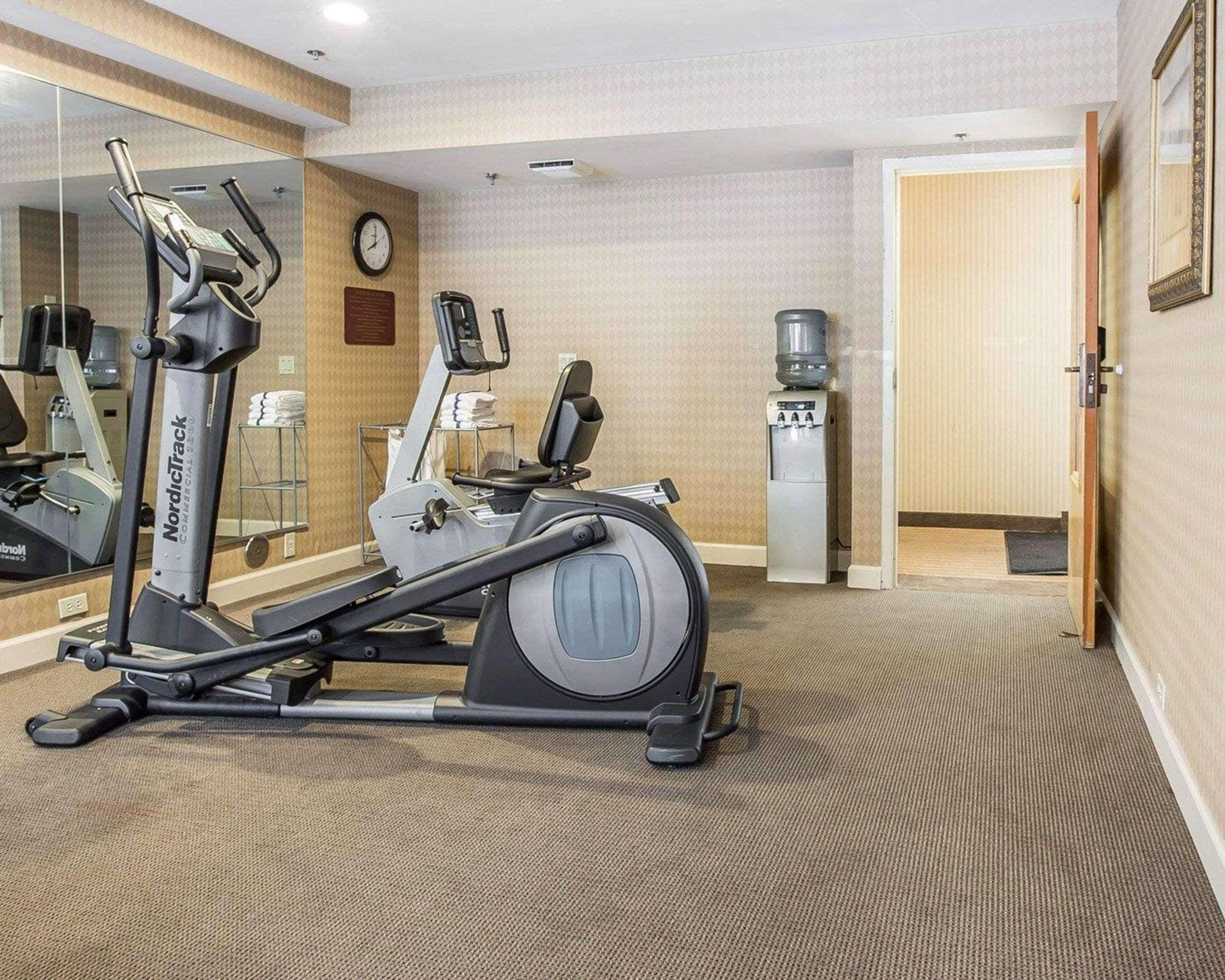 A gym with a NordicTrack elliptical, a water dispenser, and a clock on the wall.