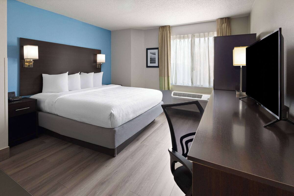 Een hotelkamer met een groot bed, een bureau met een televisie en een stoel.