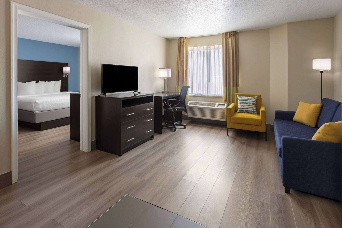 Een hotelkamer met een bed, een bureau met televisie, een stoel, een bank en een raam met gordijnen.
