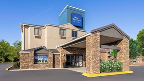 Edificio del Baymont Inn & Suites con fachada de piedra, amplia entrada y cielo azul despejado.