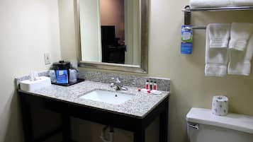 A bathroom with a granite countertop sink, a mirror, a towel rack, and a toilet.