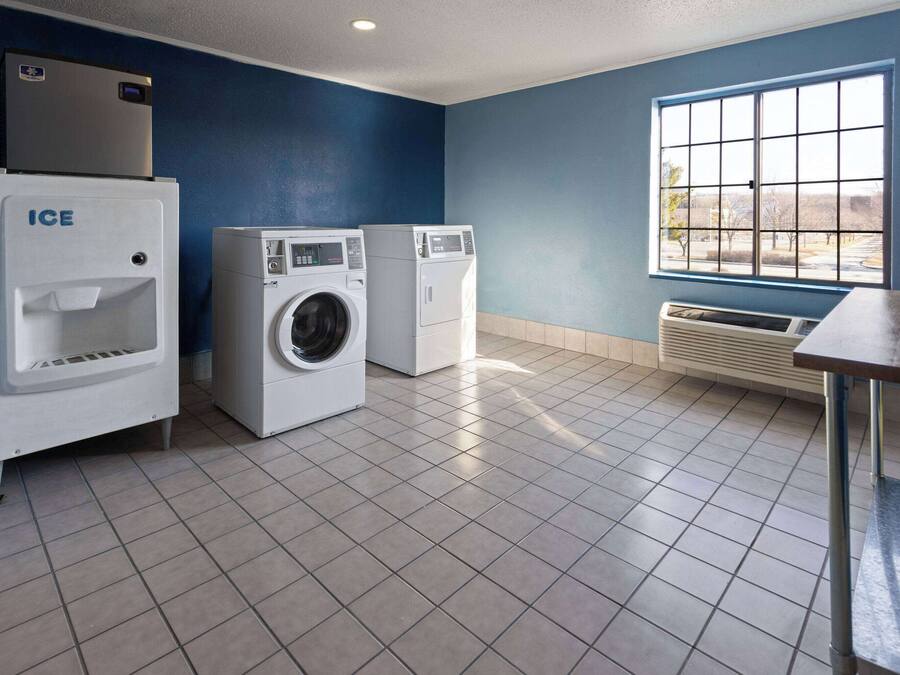 A laundry room with a large window, a water heater, and two washing machines.