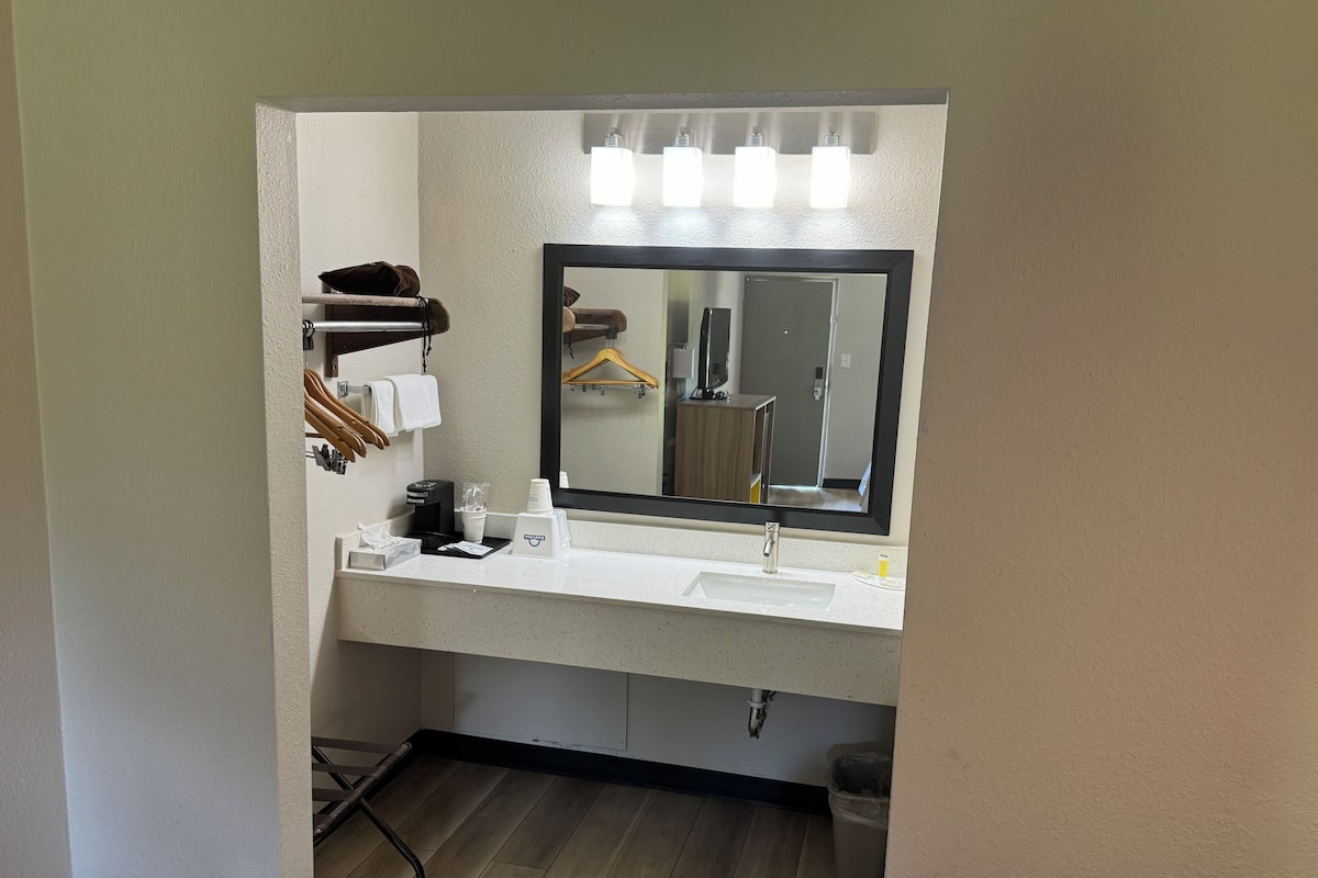 A hotel bathroom with a white sink, a mirror, and a towel rack with hanging towels.