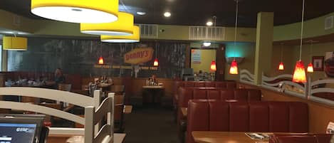 A restaurant interior with booths and tables, a cash register, and a 'Denny's' sign.