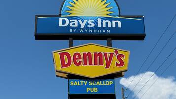 A sign for Days Inn by Wyndham, featuring a logo and the name 'Denny's' below it, with 'SALTY SCALLOP PUB' and 'MARINA' written underneath.