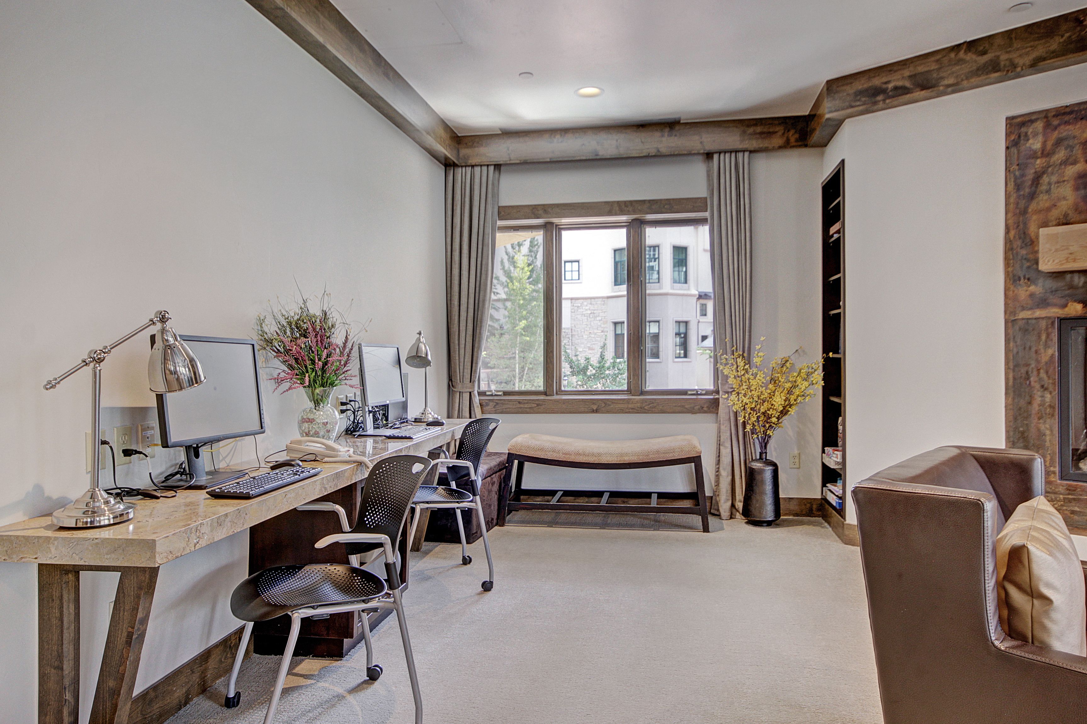 A modern hotel room with a desk, computer, and seating area.