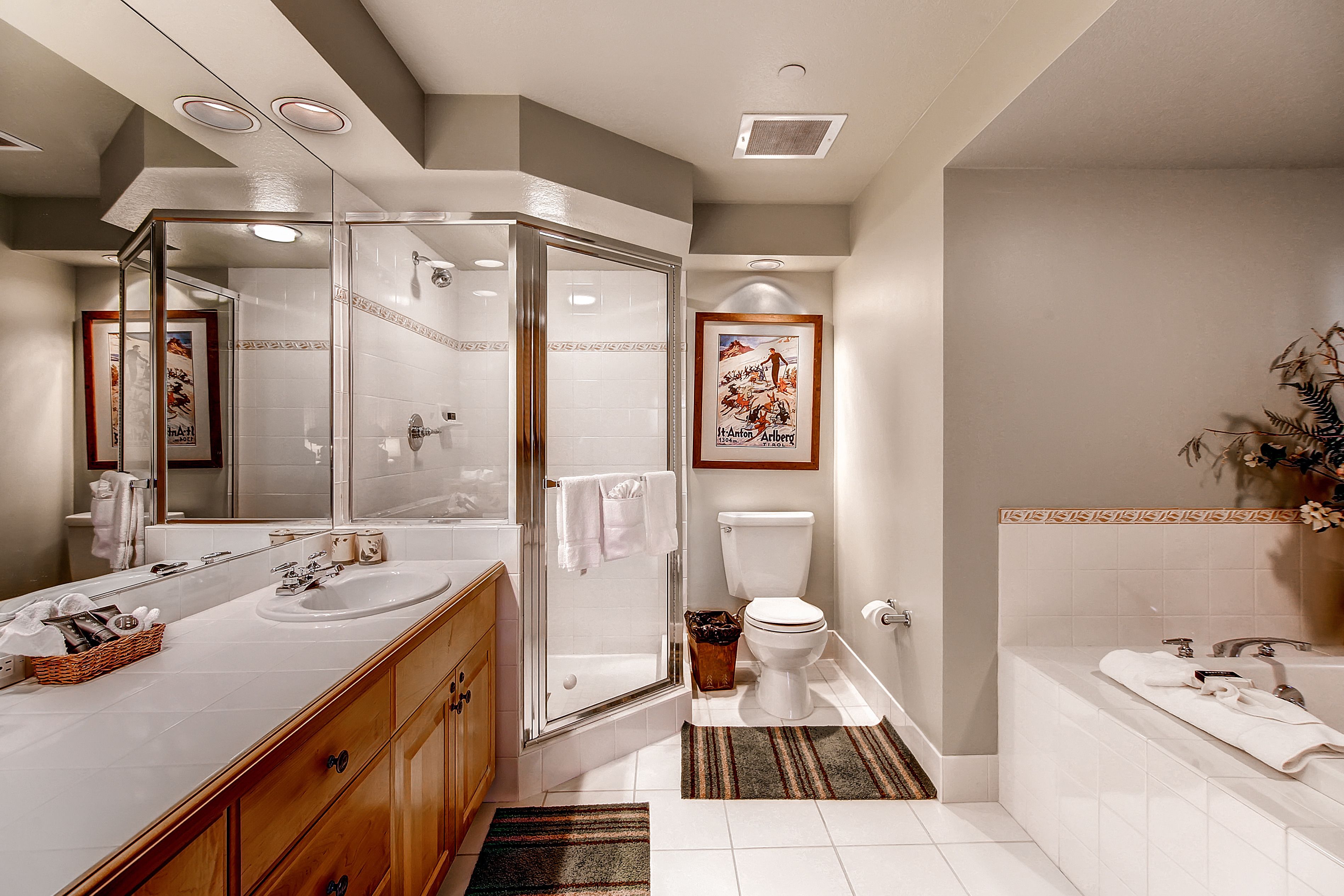 A modern bathroom with a glass-enclosed shower, a double sink vanity, a toilet, and a bathtub.